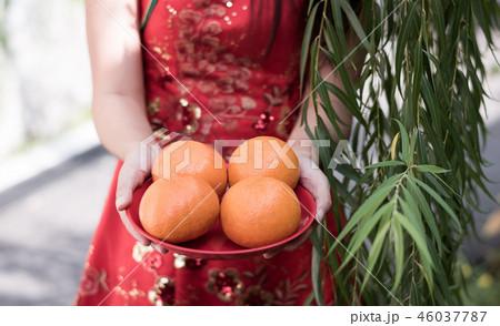 young Chinese woman holding oranges in red dress 46037787