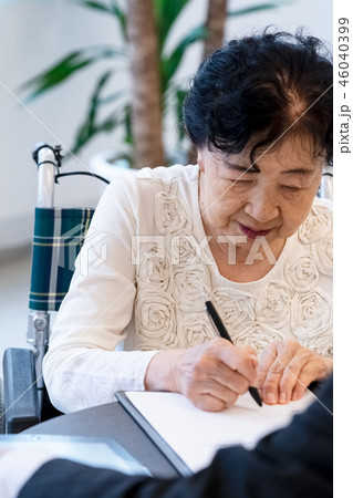 シニアイメージ　書類にサインをするシニア女性 46040399