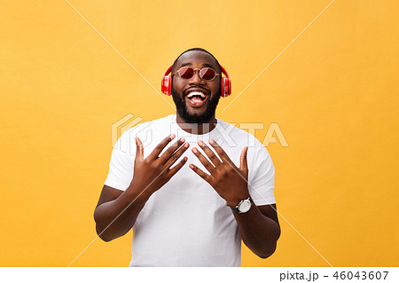 Handsome young African American man listening and smiling with music on his mobile device. Isolated 46043607