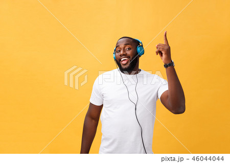 Young African American man wearing headphone and enjoy music dancing over yellow gold Background 46044044