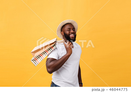 Happy african american man holding shopping bags on yellow background. Holidays concept 46044775