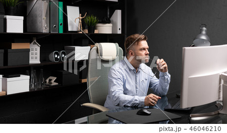 Business man sitting in office at computer Desk and holding his mouth shackle of glasses 46046210