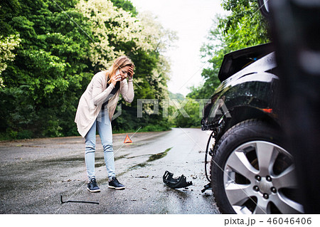 Young woman by the damaged car after a car accident, making a phone call. Young woman by the damaged car after a car accident, making a phone call. 46046406