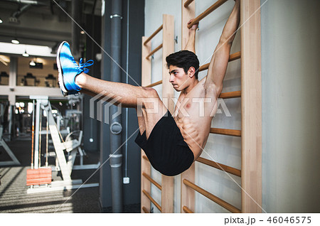 Fit young man in gym working out on wall bars. 46046575