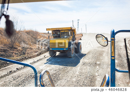 Old yellow dump truck moving in a mine 46046828