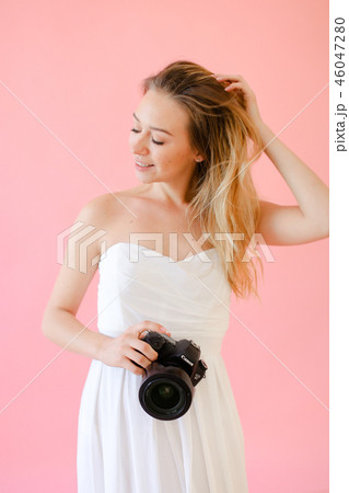 Young cute female photographer with camera in pink monophonic background. 46047280