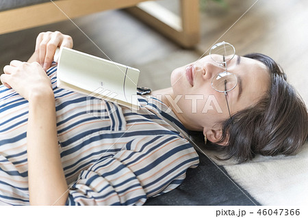 女性がフローリング床に横たわり寝そべる読書スタイルでリラックスした休日のキャリアウーマンの癒し 46047366