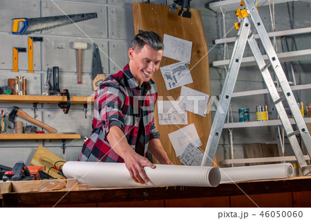 A carpenter works. Carpenter studying drawing project. Against the background of the workshop 46050060
