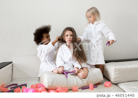 Little girls play with hair curlers and hairpins. Little girls play with hair curlers and hairpins. 46051440