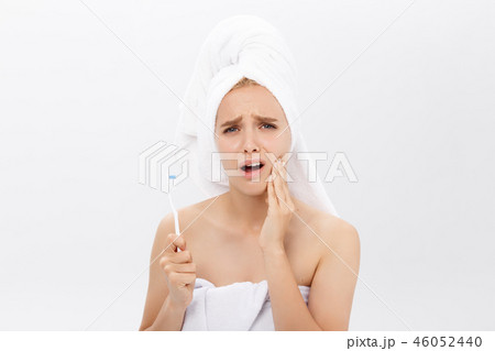 Young caucasian woman with toothache while brushing her teeth Young caucasian woman with toothache while brushing her teeth 46052440