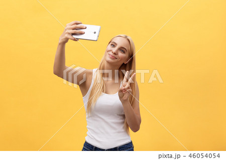 Self portrait of charming cheerful girl shooting selfie on front camera gesturing v-sign peace 46054054