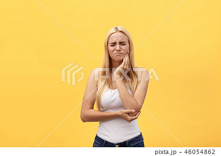 Beautiful young woman suffering from toothache on yellow background Beautiful young woman suffering from toothache on yellow background 46054862