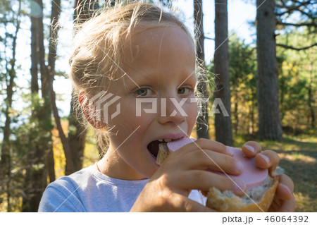 Close up portrait of a beautiful young girl enjoying and eating a fresh sandwich during a summer Close up portrait of a beautiful young girl enjoying and eating a fresh sandwich during a summer 46064392