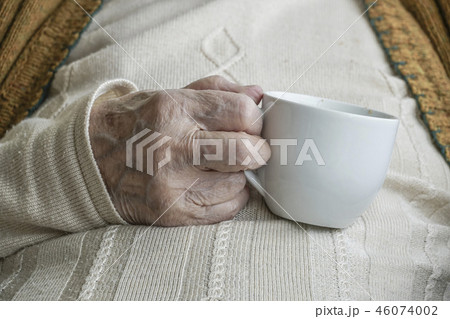 wrinkled hand holding a cup of tea wrinkled hand holding a cup of tea 46074002