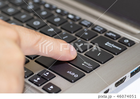 ノートパソコンのエンターキーを指で押す 46074051