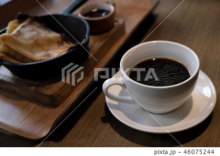 A cup of coffee and pancakes in a cast iron pan. A cup of coffee and pancakes in a cast iron pan. 46075244