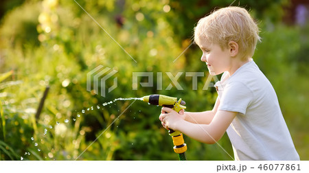 Funny little boy playing with garden hose Funny little boy playing with garden hose 46077861