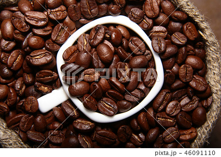 Fresh roasted coffee beans in burlap sack, coffee cup and grinder on dark background. 46091110