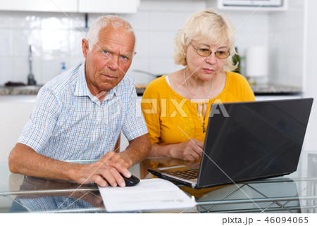 Portrait of a mature family couple looking at laptop at kitchen Portrait of a mature family couple looking at laptop at kitchen 46094065