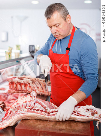 Serious seller splitting of pig carcass in shop 46094351