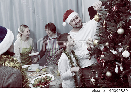 Family decorating Christmas tree and setting table Family decorating Christmas tree and setting table 46095389