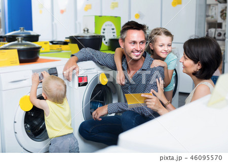 Smiling parents with kids shopping modern washer Smiling parents with kids shopping modern washer 46095570