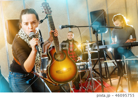 Attractive female soloist playing guitar and singing with her mu Attractive female soloist playing guitar and singing with her mu 46095755