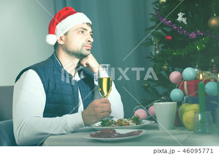 Unhappy man in hat celebrating New Year having dinner 46095771