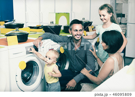 parents with two kids choosing washing machine in home appliance store parents with two kids choosing washing machine in home appliance store 46095809