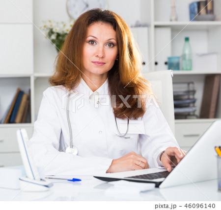 Portrait of female doctor who is working with laptop and documents 46096140