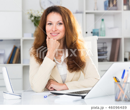 Portrait of businesswoman who is working with documents behind laptop 46096489