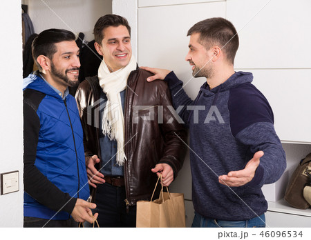 Two smiling men visiting friend at home 46096534