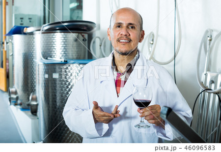 Smiling winery worker holding glass of wine Smiling winery worker holding glass of wine 46096583