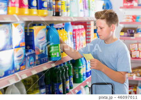 Focused tweenager boy looking household chemicals Focused tweenager boy looking household chemicals 46097011