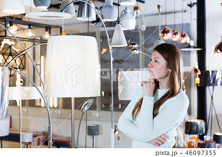 Portrait of cheerful girl buyer choosing floor lamp 46097355