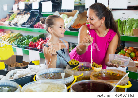 Woman with girl buying pickled olives Woman with girl buying pickled olives 46097363