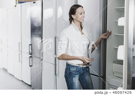 Happy woman looking at new refrigerator Happy woman looking at new refrigerator 46097426