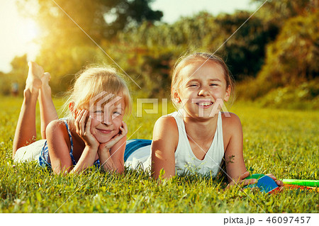 Two sisters resting on green grass 46097457