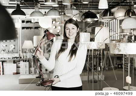 Positive girl holding table lamp in the furniture store 46097499