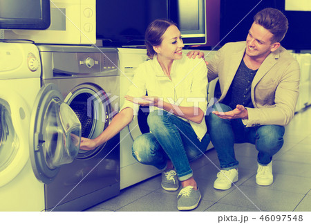 Positive customers looking at laundry machine Positive customers looking at laundry machine 46097548
