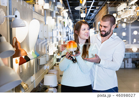Smiling couple customers choosing bedside lamp in furniture store Smiling couple customers choosing bedside lamp in furniture store 46098027