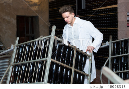 Male employee transferring bottles of wine to storage Male employee transferring bottles of wine to storage 46098313
