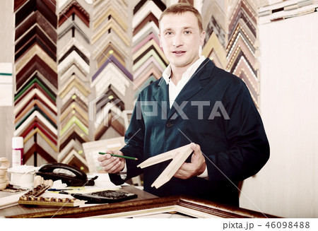 portrait of man seller working with picture frames in atelier portrait of man seller working with picture frames in atelier 46098488