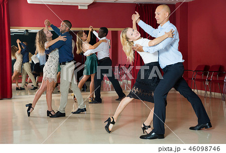 Positive adult couples dancing tango together in modern studio Positive adult couples dancing tango together in modern studio 46098746
