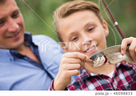 Smiling teenage boy catching on hook fish Smiling teenage boy catching on hook fish 46098833