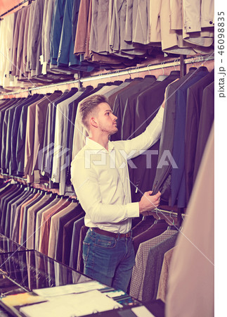 Young man choosing new suit in men’s cloths store Young man choosing new suit in men’s cloths store 46098835