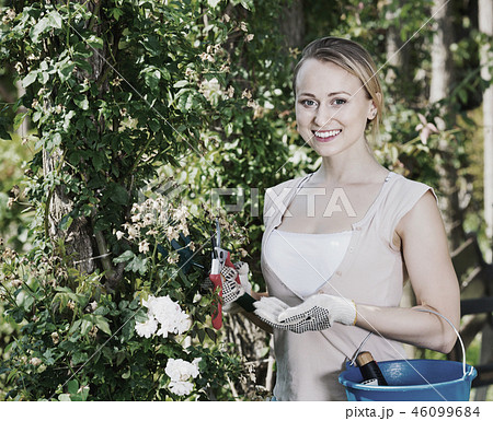Glad woman having horticultural instruments in garden 46099684