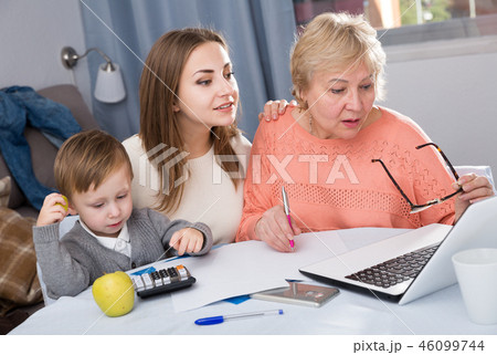 Woman is talking her mother how to fill utility bills with laptop Woman is talking her mother how to fill utility bills with laptop 46099744