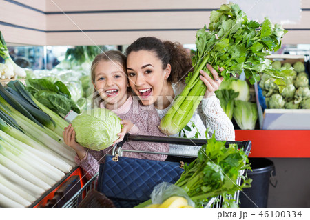 Young positive female and little girl shopping green veggies Young positive female and little girl shopping green veggies 46100334