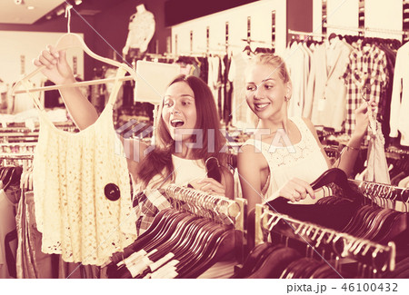 two girls buying tops in clothes store . 46100432